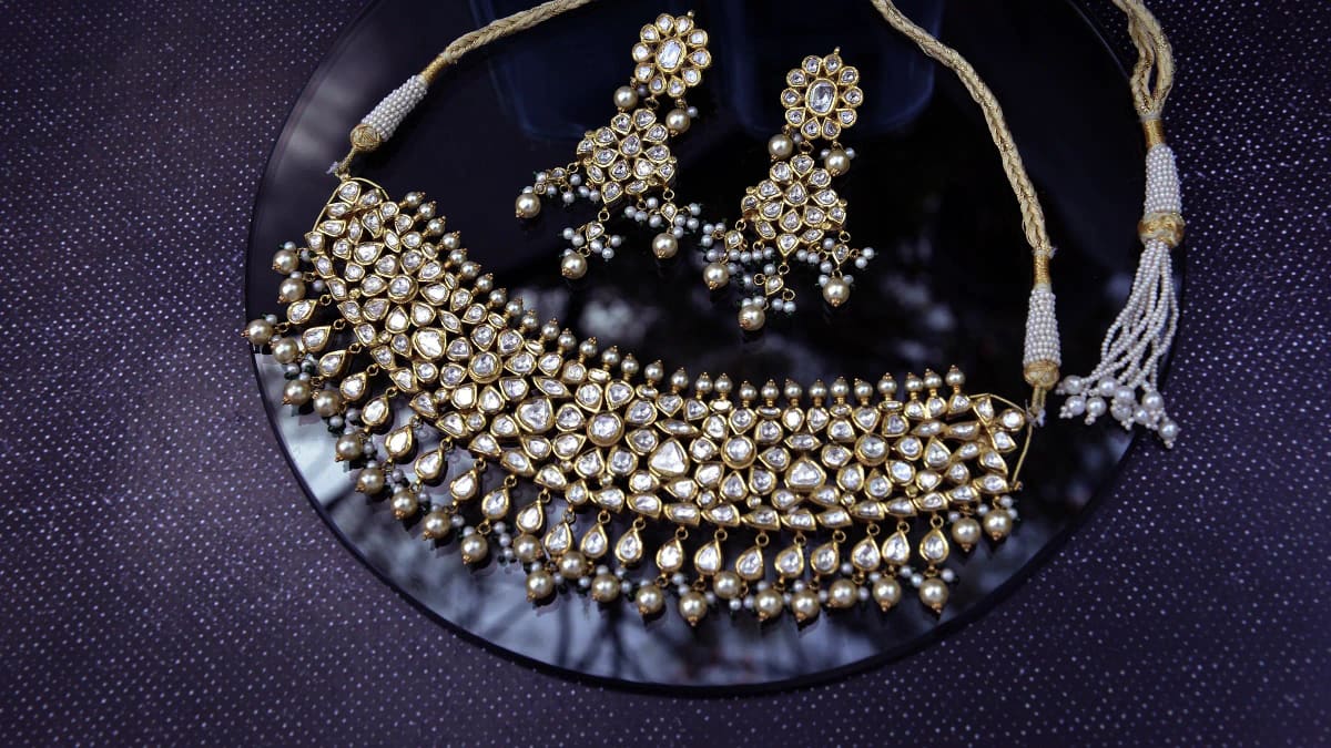 A polki bridal set laid out on a dark reflective surface